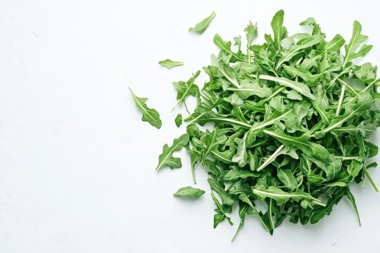Bowl of arugula on white surface seen from above