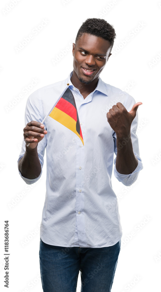 Sticker Young african american man holding german flag pointing with hand and finger up with happy face smiling