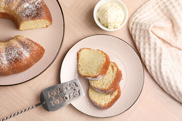 Pieces of freshly baked sponge cake, server and ice cream on wooden table, top view