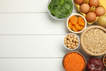 Different products rich in iron on white wooden table, flat lay. Space for text