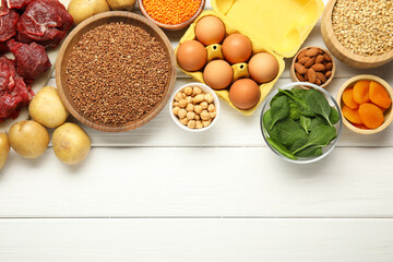 Different products rich in iron on white wooden table, flat lay. Space for text