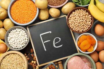 Diet plan for anemia. Different products rich in iron and small chalkboard with Ferrum symbol on table, flat lay. Space for text