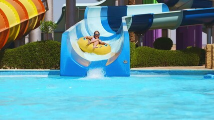  A teenage girl slides down a slide in a water park.