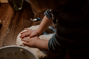 Kind knetet Pizzateig und hilft beim Backen in der Küche