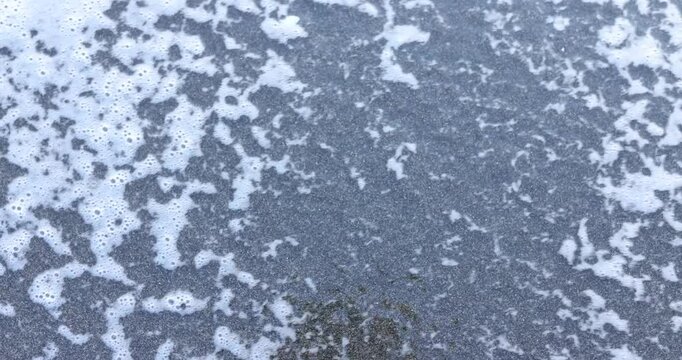 Soft white sea foam gently washes over dark sand with word Fear on summer day. Concept of illusory nature of people emotions affecting life