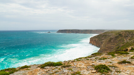 A steep cliff coastline with a beautiful blue ocean under an overcast sky, looking North from the vicinity of West Cape lighthouse on the Yorke Peninsula in South Australia.