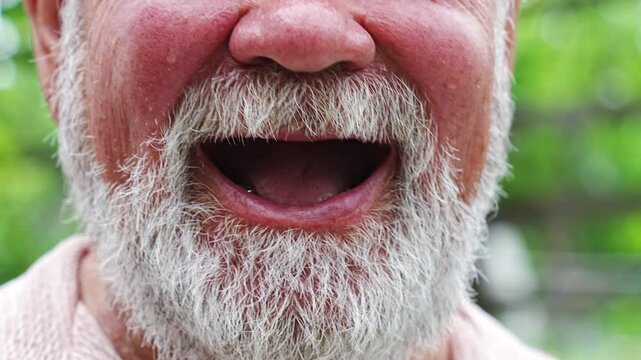 The elderly man laughs with a toothless smile. 