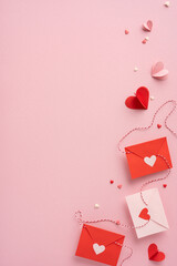 Red and white vertical envelopes with heart cutouts placed on a pink background, symbolizing love...