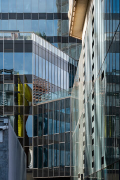 This photograph showcases various reflective surfaces of modern buildings, creating a chaotic yet beautiful visual mix, highlighting the dynamic nature of urban architecture.