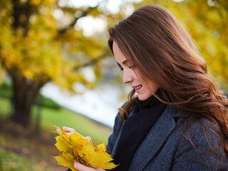 Girl, autumn image near yellow leaves in gray coat. Riga, Latvia. High quality photo