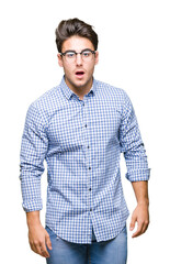 Fototapeta premium Young handsome man wearing glasses over isolated background afraid and shocked with surprise expression, fear and excited face.