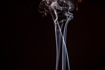 Wisps of white smoke curling gracefully against a dark background