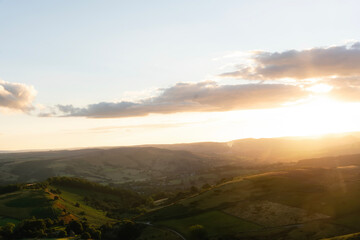 Sunset over rolling hills with dramatic clouds in a serene countryside landscape