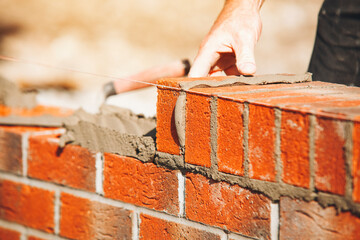 Close-up of Skilled masonry work in progress featuring brick laying and mortar application outdoors