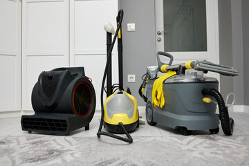 A professional cleaning vacuum cleaner, a steam mop and a hair dryer for drying carpets are in the...