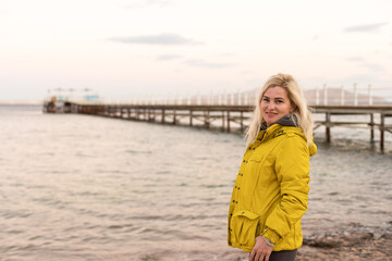 Woman in jacket near sea at sunrise cold morning