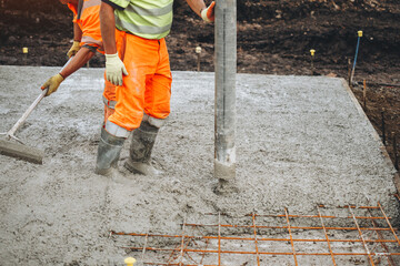 Workers pouring concrete to create a solid foundation at a construction site during daylight