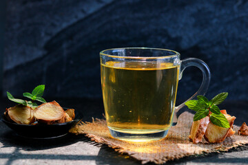 A cup of ginger tea with mint on a dark background