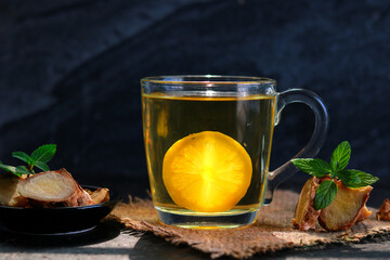 Cup of ginger tea with lemon and mint on a black background