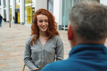Young woman smiles while conversing with an older man in an urban outdoor setting