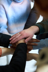 A top view of business people joining hands in a circle, symbolizing unity, collaboration, and shared success in the workplace