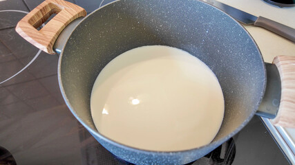 A pot of milk heating on a modern stovetop, perfect for cooking recipes or preparing holiday desserts