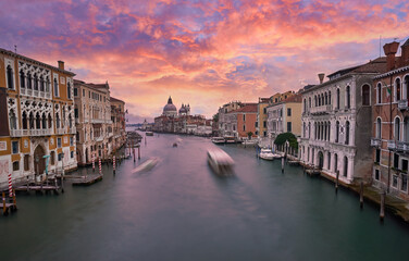 Old canal with bridge, gondola, houses, flowers in cloudy weather. Venice