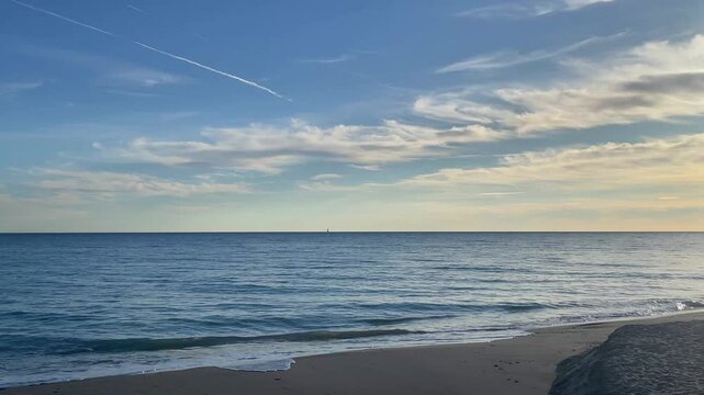 Serene Catalonia beachscape: soft waves, blue sky, peaceful mood, Altafulla.