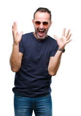 Naklejka premium Middle age hoary senior man wearing sunglasses over isolated background celebrating crazy and amazed for success with arms raised and open eyes screaming excited. Winner concept