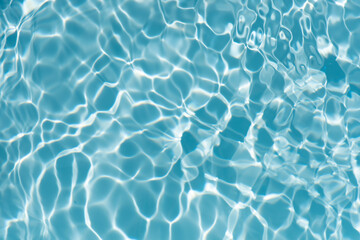 Blue water with ripples on the surface. Defocus blurred transparent blue colored clear calm water surface texture with splashes and bubbles. Water waves with shining pattern texture background.