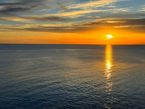 Calm blue sea and orange sunset sky clouds at evening. 