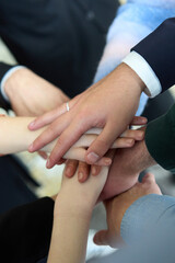 A top view of business people joining hands in a circle, symbolizing unity, collaboration, and shared success in the workplace