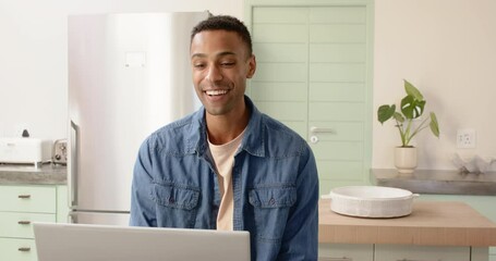 Smiling man using laptop in kitchen, enjoying video call at home - Powered by Adobe