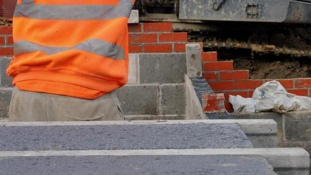 Construction worker laying bricks for a new structure at a building site in a residential area