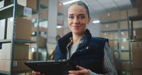 Female Inventory Manager in Warehouse Facility: Uses Tablet Computer, Looks at Camera. Sorting Worker Preparing Online Orders for Shipping. Delivery Service, Logistics Distribution Center. Portrait.