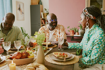 Adorable wife sitting at table having conversation with her beloved husband while having family dinner