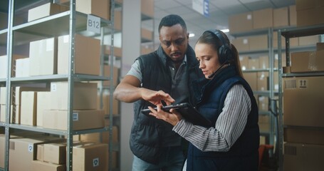 Female Logistics Coordinator Wearing Headset Uses Tablet Computer in Warehouse Facility, African American Supervisor Helps Colleague. Logistics Distribution Center with E-Commerce Orders. Dolly Shot.
