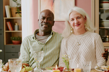Medium close up portrait of biracial couple sitting at table, African American man hugging his beloved Caucasian wife
