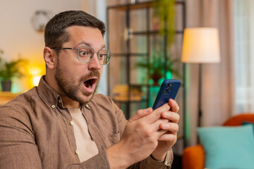 Oh my God, Wow. Caucasian young businessman using smartphone shocked by sudden victory game...