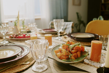 Medium close up of polished crystal glass near plate with baked potatoes on served festive table