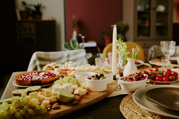 Medium close up of oval wooden plate with different types of cheese on table served with perfect polished kitchenware