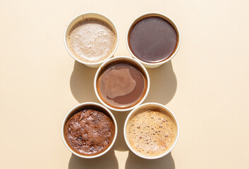 A range of coffee drinks in disposable paper cups, highlighting coffee diversity and convenience.