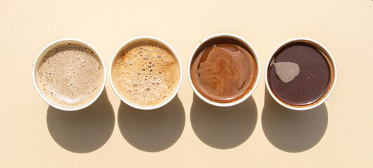 A variety of coffee beverages, from lattes to black coffee, displayed in takeaway cups.
