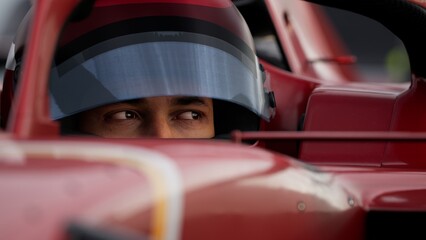 Close-up of a focused pilot driver in a red racing car, preparing for a race