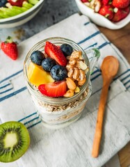 Preparing healthy breakfast for kids with yogurt, granola, and fresh fruits