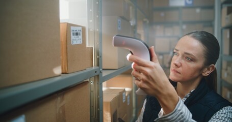 Female Warehouse Associate Scans Cardboard Box with E-Commerce Goods with Scanner, Checks...