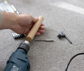 Man holding modern electric drill on gray carpet. top view.