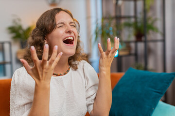 Sad woman feeling hopelessness loneliness nervous breakdown, crying shouting sitting on sofa in...