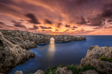 A view of the famous place of Pont d'en Gil stone arch on the island of Menorca at sunset from the...