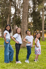 Four girls are standing in a park, posing for a picture